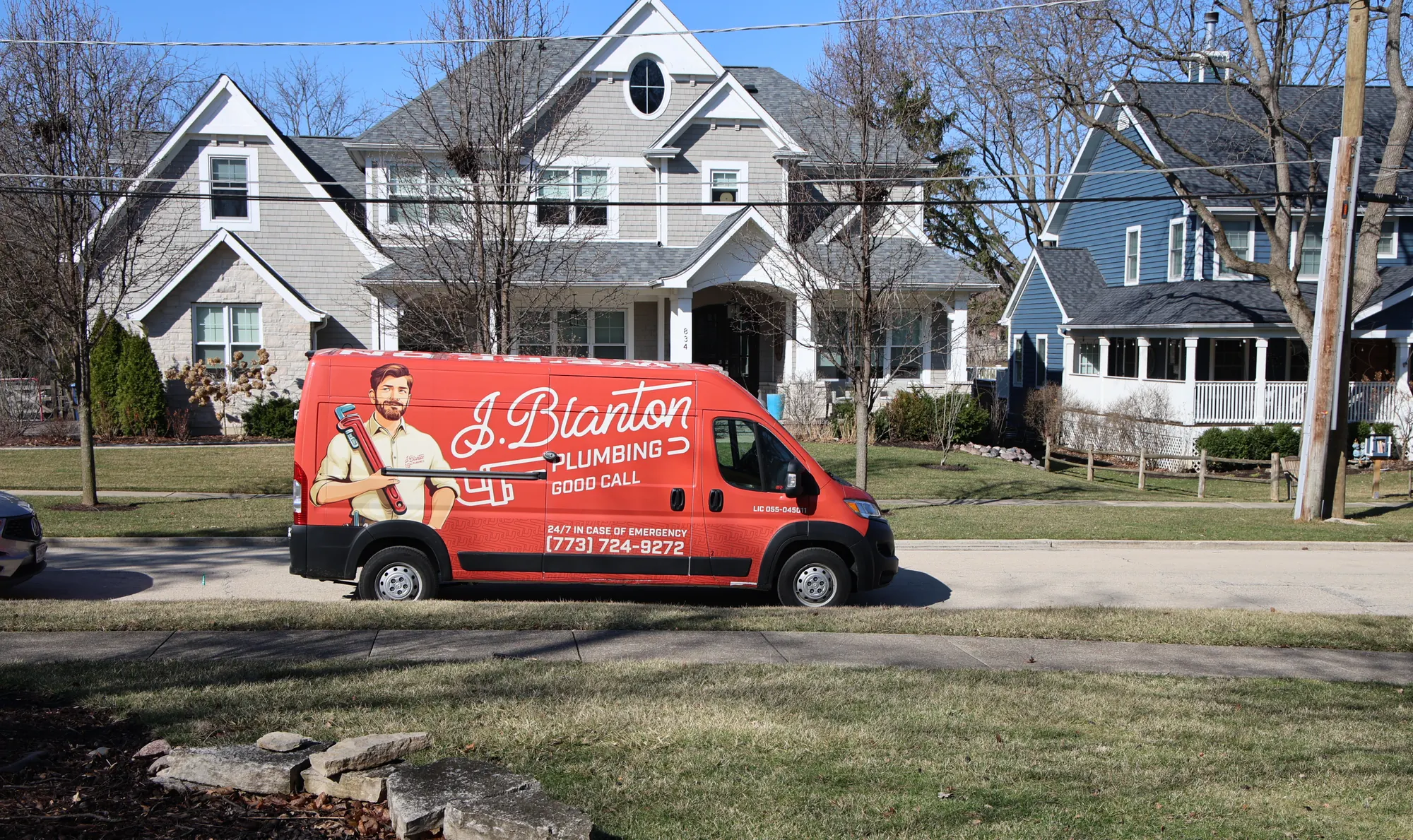 J. Blanton Plumbing van parked on a residential street in front of a two-story home