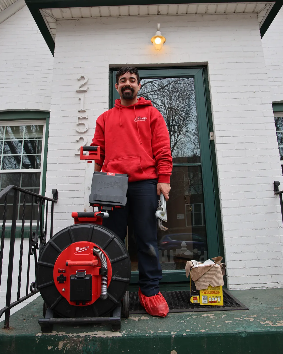 J. Blanton plumber in shoe covers on a home's front steps with a sewer camera